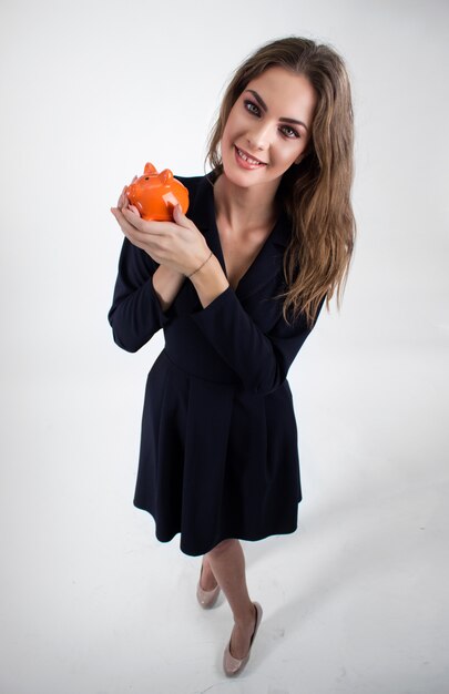 Happy businesswoman holding piggy bank against white background