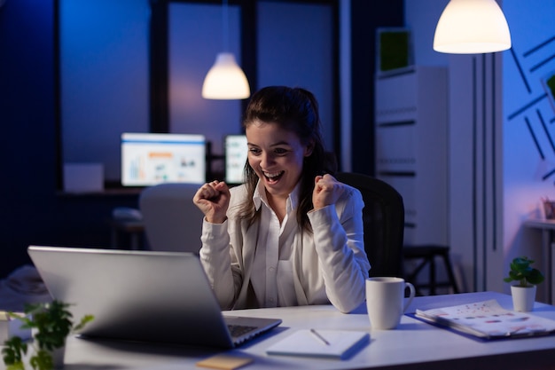 Счастливая деловая женщина, читающая отличные онлайн-новости на ноутбуке, работает над экономическими возможностями в офисе запускаемой компании