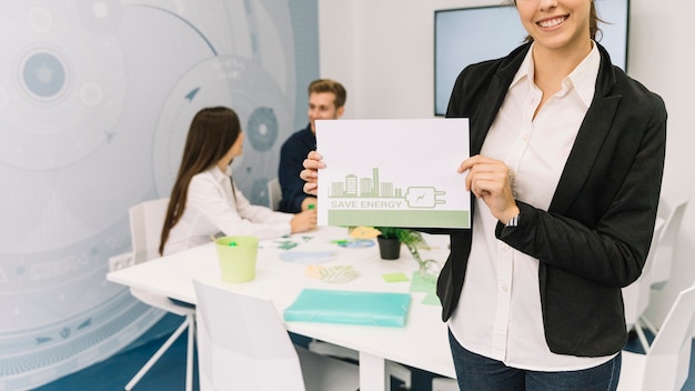 Happy businesswoman showing energy saving concept on paper