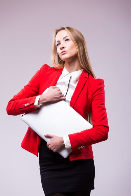 Happy businesswoman standing with laptop isolated on a white wall. 