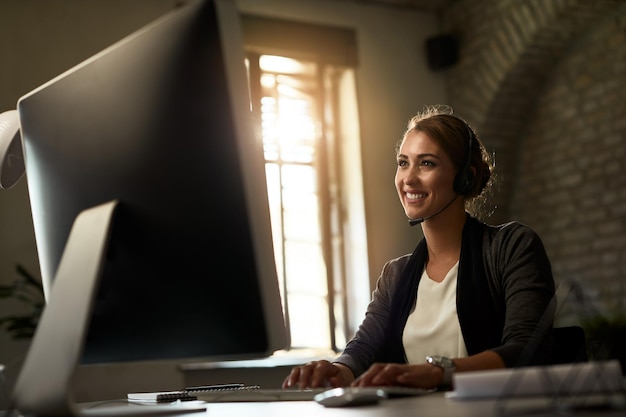 Happy businesswoman typing an email on desktop PC in the office