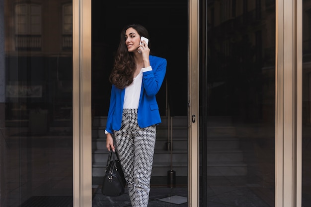 Happy businesswoman with mobile phone in the entrance hall