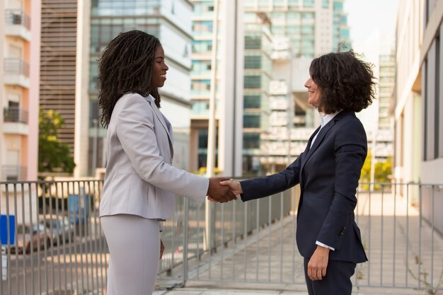 Happy businesswomen shaking hands outside