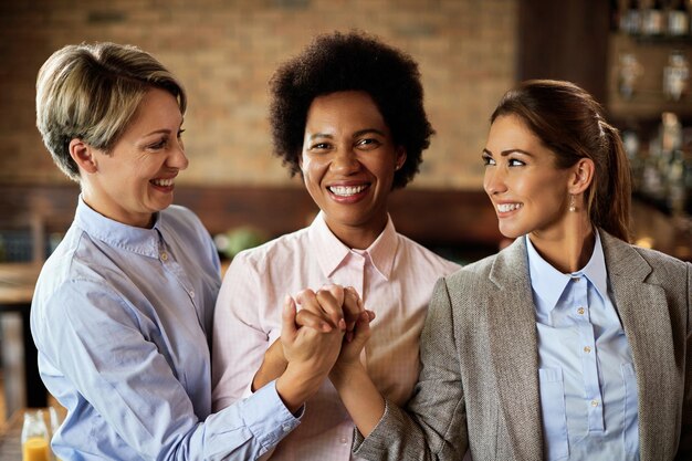 Счастливые деловые женщины поддерживают друг друга и держатся за руки в кафе