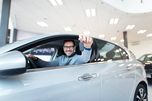 Happy buyer sitting in new vehicle and holding car keys