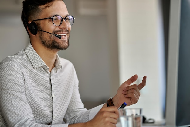 Happy call center agent using computer while communicating with clients and working in the office