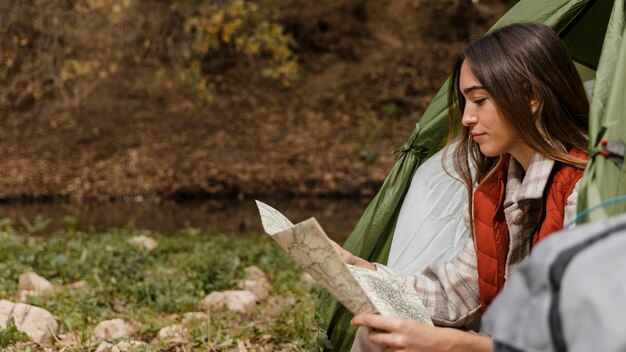 地図の側面図を確認して森の中で幸せなキャンプの女の子