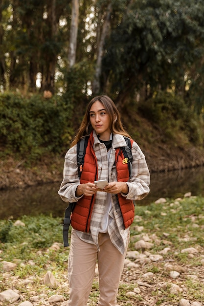 Free photo happy camping girl in the forest holding mobile phone