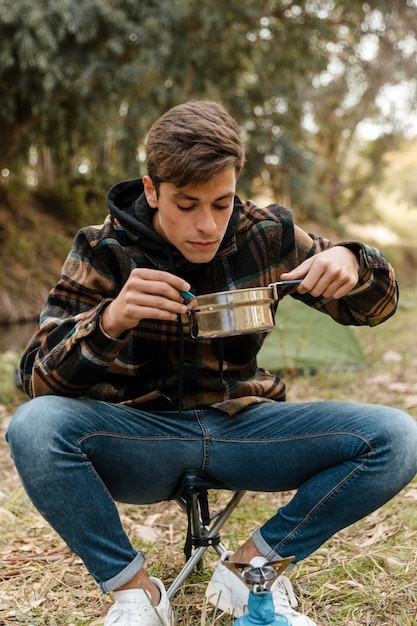 Foto gratuita uomo di campeggio felice nella foresta che mangia