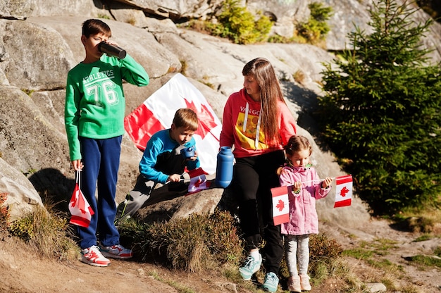 ハッピーカナダデー。 3人の子供を持つ母親の家族は、山で大規模なカナダ国旗のお祝いを開催します。 Premium写真