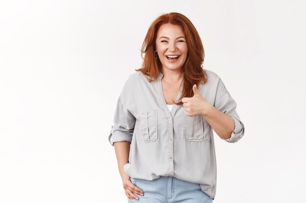 Happy carefree good-looking redhead middle-aged 50s woman laughing joyfully have fun approve show thumb up satisfied good joke standing white wall cheering