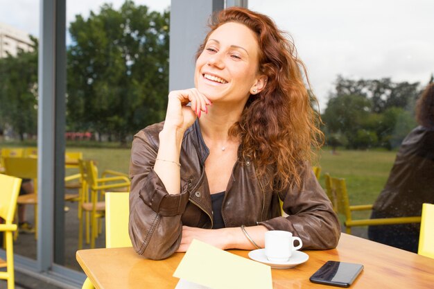Счастливая беззаботная женщина, наслаждаясь утром в кафе на открытом воздухе