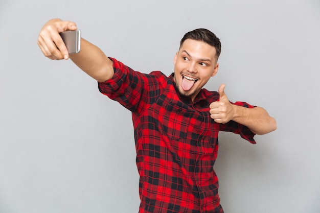 Selfieを作る格子縞のシャツで幸せなカジュアルな男