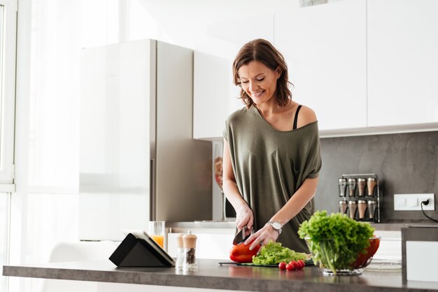 Happy casual woman cutting vegetables