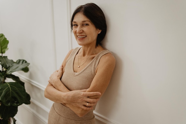 Happy caucasian adult brunette lady with cute toothy smile looks at camera with arms crossed Leisure lifestyle and beauty concept