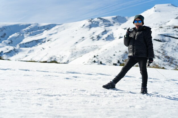 Happy Caucasian boy wearing warm clothes on the snowy mountain in the winter