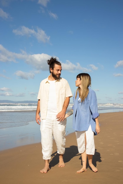 Happy Caucasian couple strolling along seashore