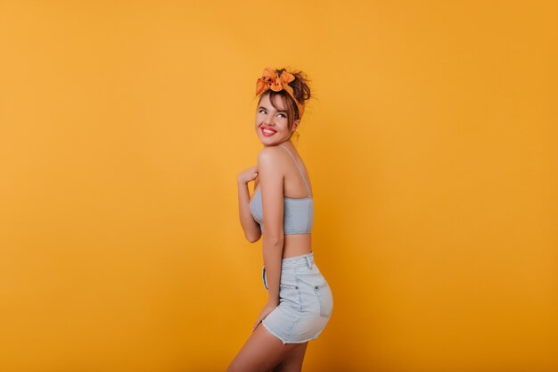 Happy caucasian girl in summer outfit looking away while posing 