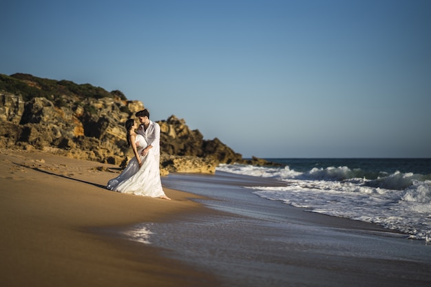 結婚式の写真撮影中にビーチで白い抱擁を身に着けている幸せな白人愛情のあるカップル