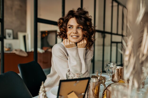 Happy charming girl with curly hairstyle smiling with happy emotions waiting for Christmas