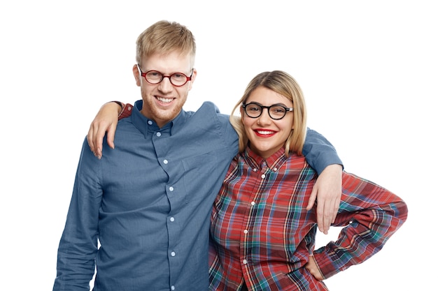 happy cheerful best friends male and female wearing stylish oval eyewear embracing and smiling broadly while posing for picture after long separation, glad to finally see each other