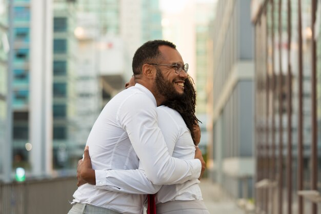 Happy cheerful business man hugging female friend