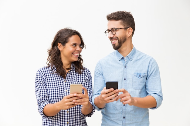 Happy cheerful couple with cellphones chatting