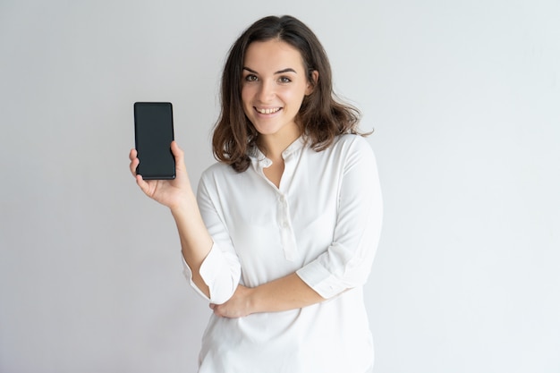 Happy cheerful girl presenting new app on cellphone screen.