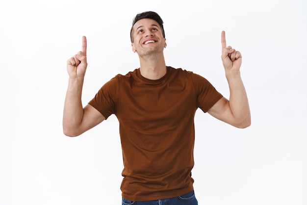 Free photo happy cheerful handsome adult man raising head up looking and pointing fingers at top advertisement with pleased smile found excellent choice best deal in internet checkout banner