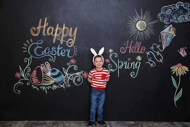 Happy cheerful little boy wearing bunny ears and celebrating easter