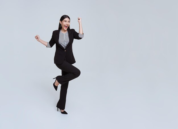 스튜디오 흰색 배경에 공중에서 점프하는 양복에 행복 쾌활 한 젊은 아시아 사업가
