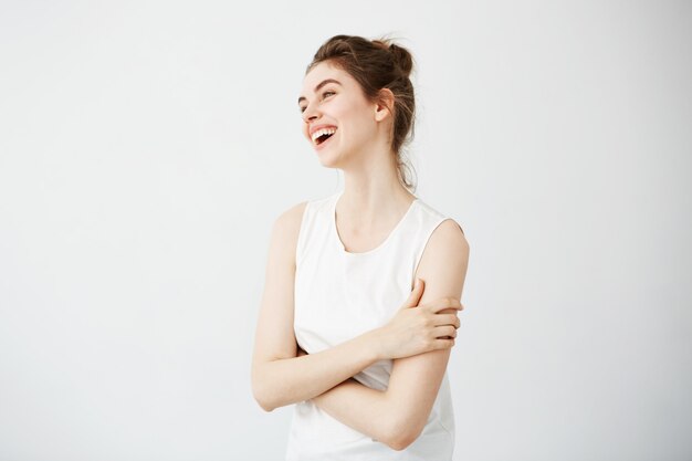 Happy cheerful young woman with bun smiling laughing. Crossed arms.