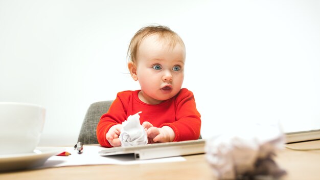 白で隔離現代のコンピューターまたはラップトップのキーボードで座っている幸せな子女の赤ちゃん