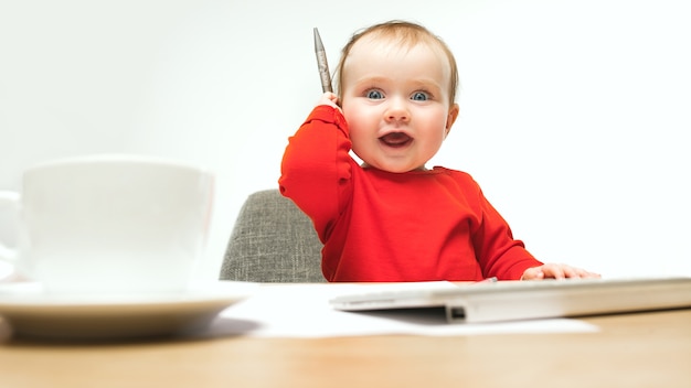 Free photo happy child baby girl sitting with pen and keyboard of modern computer or laptop isolated on a white studio