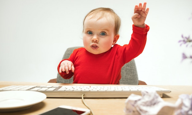 Happy child baby girl toddler sitting with keyboard of computer isolated