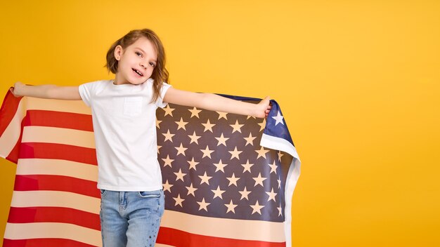 黄色いアメリカのアメリカ国旗を持つ幸せな子かわいい女の子が独立記念日を祝う プレミアム写真