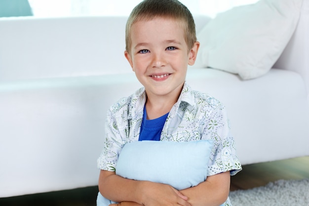 Free photo happy child hugging a pillow