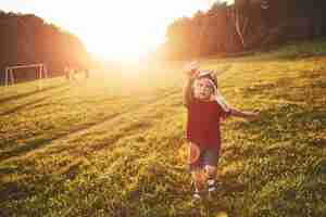 Free photo happy child launch a kite in the field at sunset. little boy and girl on summer vacation