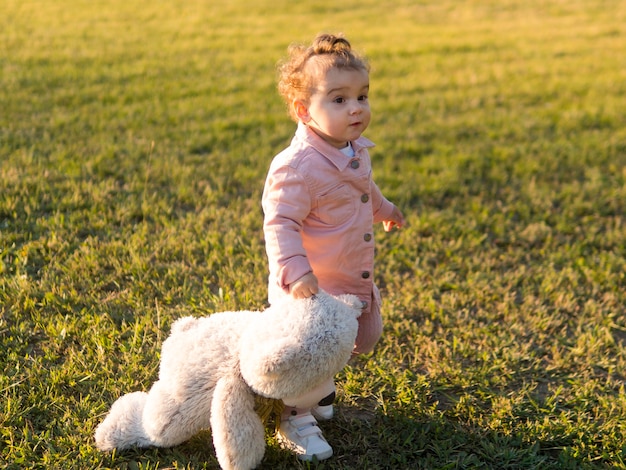 Happy child in pink clothes and his friendly toy