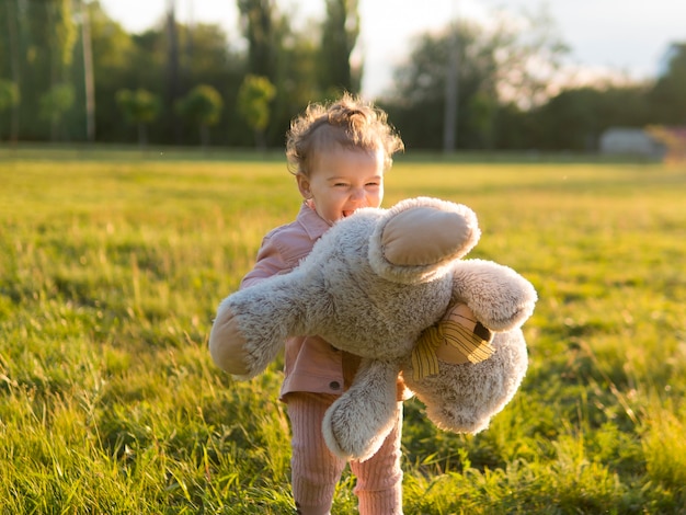 Happy child in pink clothes holding a teddy bear
