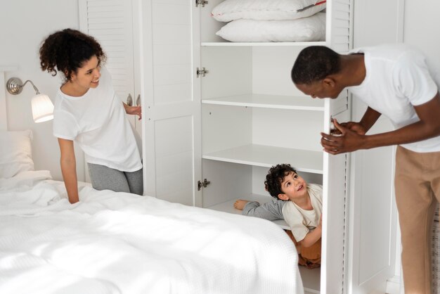 Happy child playing hide and seek with his parents