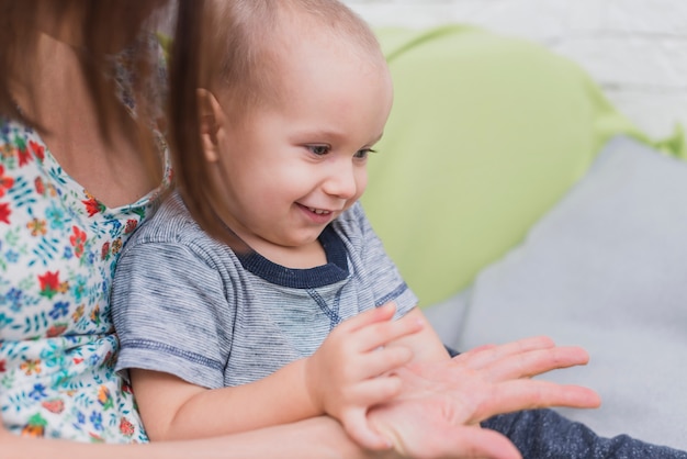 Bambino felice di giocare con la mano di sua madre