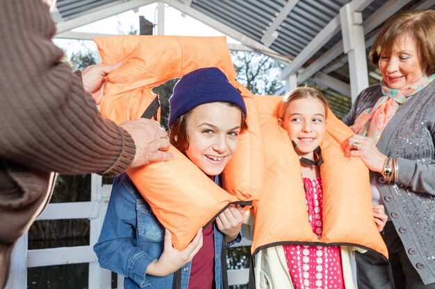 Счастливый ребенок положить оранжевый спасательный жилет