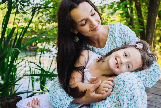 Happy child rests on mother's knees in forest 