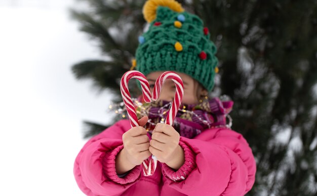크리스마스 트리 아래 큰 사탕 지팡이와 행복 한 아이. 겨울 휴가 개념.