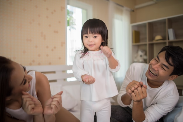 家庭のベッドで遊んでいる両親と幸せな子供