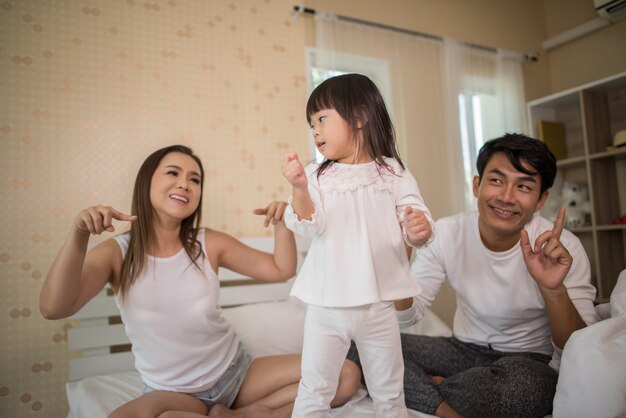 Happy child with parents playing in the bed at home