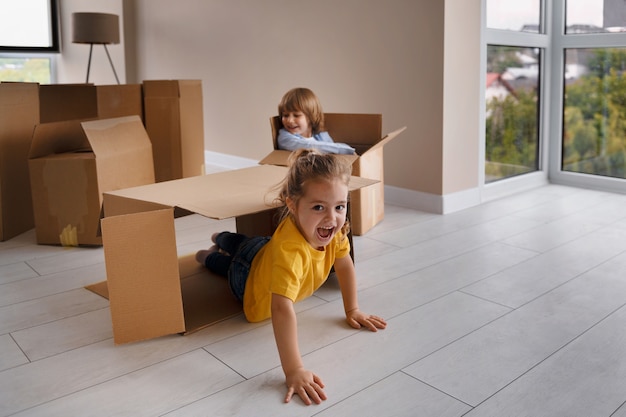 Happy children having fun with boxes in their new home