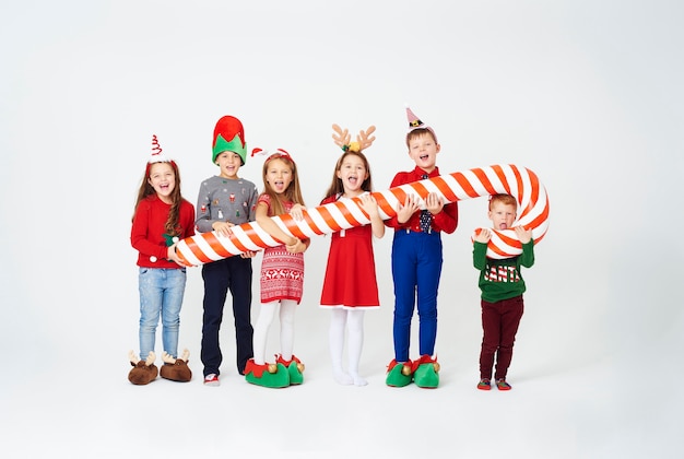 Free photo happy children holding huge candy cane