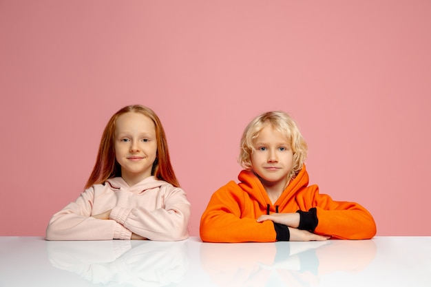 Bambini felici isolati su sfondo rosa corallo studio. sembra felice, allegro, sincero. copyspace. infanzia, educazione, concetto di emozioni